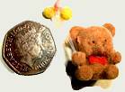 Miniature teddy-bear beside a 50p coin.