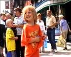 Smiling little girl dancing to a street busker.